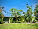 Charming single-story home with lush landscaping and a vibrant yellow exterior at 850 Van Gogh Road, Englewood, FL 34223