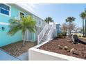 Side exterior of house with blue siding, white trim, and landscaped yard with palm trees and stone accents at 9230 Pine Cove Dr, Englewood, FL 34224