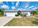 Charming home featuring a manicured lawn, mature landscaping, and an attached two-car garage at 115 Australian Dr, Rotonda West, FL 33947