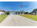 Well-maintained one-story home with a two-car garage, manicured lawn, and a classic American flag at 1278 Lincoln Dr, Englewood, FL 34224
