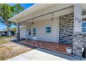 View of the home's front porch, featuring tiled flooring, hanging lights, and decorative stone pillars at 150 Crestview Dr, Englewood, FL 34223
