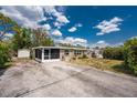 Charming single-story home with a screen porch, storage shed, and a long driveway, surrounded by lush trees at 1530 Philip Pl, Englewood, FL 34223