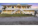 Two-story yellow waterfront home featuring a large front yard, dual staircases, and a two-car garage at ground level at 1905 Mississippi Ave, Englewood, FL 34224