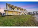 Spacious two-story yellow waterfront home with expansive balconies and lush landscaping, offering beautiful bay views at 1905 Mississippi Ave, Englewood, FL 34224