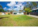 Expansive backyard featuring a well-maintained lawn, shed, driveway, and lovely white house with a light blue accent awning at 221 Nippino E Trl, Nokomis, FL 34275