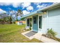 Charming house entrance featuring a light blue door and awning, framed by lush greenery and a well-manicured lawn at 221 Nippino E Trl, Nokomis, FL 34275