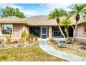Welcoming front entrance with a paved walkway, potted plants, and charming palm trees, creating curb appeal at 533 Boundary Blvd, Rotonda West, FL 33947