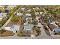 A sprawling aerial view of a light blue single-story home nestled in a tree-lined neighborhood with nearby amenities at 7035 Duke St, Englewood, FL 34224