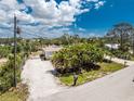 An aerial perspective showcases the property's surroundings with its lush greenery and gravel driveway at 7035 York St, Englewood, FL 34224
