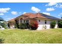 A lovely home is displayed from an angle that highlights its tile roof and beautifully landscaped yard at 76 Sportsman Rd, Rotonda West, FL 33947