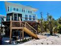 A beautiful stilted home with a deck, stairs, and lush tropical plants at 8152 Little Gasparilla Is, Placida, FL 33946