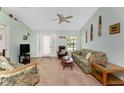 Inviting living room with neutral carpet and light green walls, featuring a ceiling fan and ample seating at 941 Allen Ave, Englewood, FL 34223