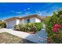 Attractive home exterior featuring a two-car garage, well-kept landscaping, and mature bougainvillea at 116 Albatross Rd, Rotonda West, FL 33947