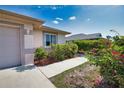 Charming home featuring beautiful landscaping with colorful bougainvillea bushes and a paved walkway to the entrance at 116 Albatross Rd, Rotonda West, FL 33947