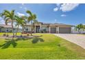 Beautifully landscaped home featuring a three-car garage and mature palm trees at 14527 Maysville Cir, Port Charlotte, FL 33981