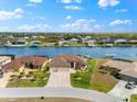 Aerial view of a home on the water with a dock, surrounded by other homes and lush greenery, all under a clear blue sky at 15588 Ruston Cir, Port Charlotte, FL 33981