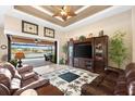 Cozy living room with stylish tile flooring, ceiling fan, large TV, and sliding glass doors with serene lake views at 15588 Ruston Cir, Port Charlotte, FL 33981