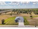 Aerial view of a well-maintained single-story home near a highway, with ample greenery and a long driveway at 16489 Trading Post Rd, Punta Gorda, FL 33955
