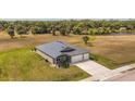 Aerial view showcases the property with lush green lawn, extended driveway, and convenient three-car garage at 16489 Trading Post Rd, Punta Gorda, FL 33955