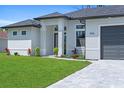 Close up of a light grey house with a gray driveway and landscaping at 1826 Narrington Ave, North Port, FL 34288