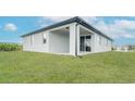 A covered back porch offers a shaded outdoor space accessible through sliding glass doors, surrounded by green grass at 234 Cougar Way, Rotonda West, FL 33947