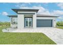 Inviting single-story home with a beautifully landscaped yard, gray roof, and stylish garage door at 234 Cougar Way, Rotonda West, FL 33947