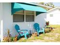 Close up on a single-story home with teal awning and chairs in front yard at 360 W Cowles St, Englewood, FL 34223