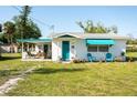 Charming single-story home featuring a covered porch, teal accents, and a well-manicured lawn at 360 W Cowles St, Englewood, FL 34223