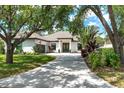 Charming single-story home with an arched entryway, tile roof, circular driveway and mature shade trees at 5 Saint John Blvd, Englewood, FL 34223