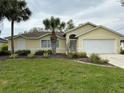 Lovely home featuring an attached garage and manicured landscaping with a decorative palm tree at 67 Marker Rd, Rotonda West, FL 33947