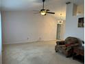 Spacious living room features plush carpeting, ceiling fan, and a modern chandelier for comfortable living at 67 Marker Rd, Rotonda West, FL 33947