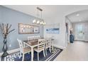 Dining room with a rectangular table, four chairs, modern light fixture, and a decorative mirror at 7620 Raptor Ct, North Port, FL 34287