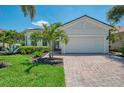 Beautifully landscaped home with lush green grass, palm trees, brick driveway and barrel tile roof at 13000 N Marsh Dr, Port Charlotte, FL 33953