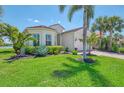 Beautifully landscaped home with lush green grass, palm trees, brick driveway and barrel tile roof at 13000 N Marsh Dr, Port Charlotte, FL 33953
