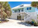 Charming stilt home with white railing, stairs, and tropical landscaping at 180 S Gulf Blvd, Placida, FL 33946