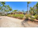 Charming single-story brick home with a lush front yard, rock driveway, and beautiful tropical landscaping at 20 Spaniards Rd, Placida, FL 33946