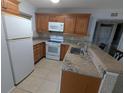 Well-equipped kitchen with granite countertops, wooden cabinetry, and modern white appliances at 25100 Sandhill Blvd # T101, Punta Gorda, FL 33983