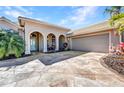 Beige home with arched entry and accent lighting sits adjacent to a two car garage at 3511 Bay Ridge Way, Port Charlotte, FL 33953