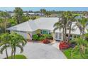 Charming yellow home with a white tile roof, paver driveway, and lush tropical landscaping, near the water at 44 Waterford Dr, Englewood, FL 34223