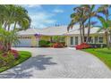 Inviting home with a well-maintained lawn and paver driveway, accented by tropical landscaping and large windows at 44 Waterford Dr, Englewood, FL 34223