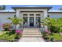 Inviting front entrance with stone steps, elegant planters, and vibrant landscaping at 4624 Pompano St, Placida, FL 33946