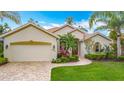 Well-maintained single-story home with a neutral color scheme, brick paver driveway, and lush landscaping at 5433 White Ibis Dr, North Port, FL 34287