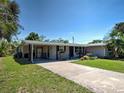 Charming single-story home featuring a covered porch, manicured lawn, and colorful flowerbeds at 6181 Jack St, Venice, FL 34293