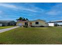 Inviting single-story yellow home featuring a lovely yard and a private driveway at 81 Oakland Hills Pl, Rotonda West, FL 33947