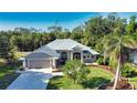 Charming home featuring a meticulously manicured lawn, lush tropical landscaping, and a welcoming two-car garage at 941 Elwood Ave, Englewood, FL 34223