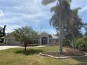 Landscaped front yard showcasing flowering plants, mature palm trees, and a well-maintained lawn, enhancing curb appeal at 941 Elwood Ave, Englewood, FL 34223