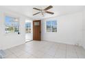 Bright living room with neutral-toned tile floors, ceiling fan, and natural light from two windows at 1167 Delmar St, Englewood, FL 34224