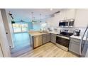Open concept kitchen features stainless steel appliances and light wood flooring with water views at 11750 Tempest Harbor Loop, Venice, FL 34292