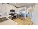 Modern kitchen featuring white cabinets, stainless steel appliances, and wood flooring at 11750 Tempest Harbor Loop, Venice, FL 34292