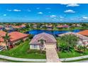 Aerial view of a beautiful single-story house near a lake and surrounded by lush landscaping in a residential community at 13335 Golf Pointe Dr, Port Charlotte, FL 33953